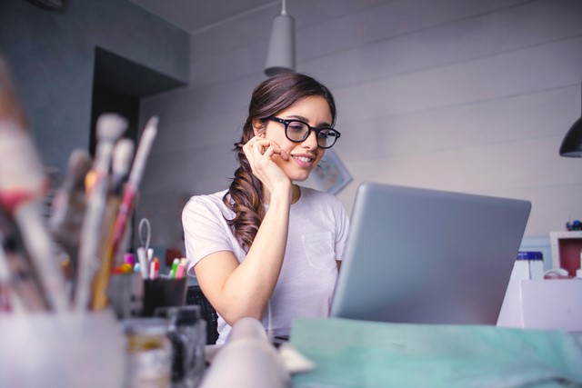 Frau sitzt im Home Office am Schreibtisch vor einem Laptop